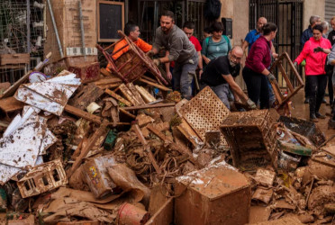 Mud-caked volunteers clean flood debris in a Spanish town as authorities struggle to respond