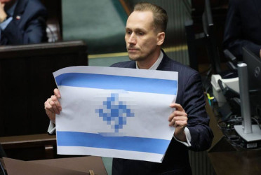 Polish MP holds altered Israeli flag in protest of Israeli crimes